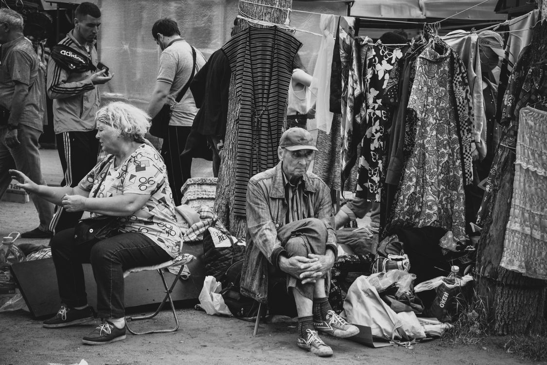 Black-and-white photograph of vendors resting at an open-air market stall